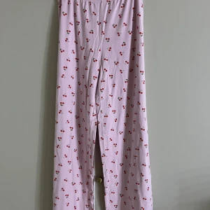 Rosa pyjamasbyxor med körsbär Gina Tricot - Säljer ett par supergulliga rosa pyjamasbyxor från Gina Tricot med körsbärsmönster över hela. Byxorna har resår i midjan och är gjorda i mjuk bomull, perfekta för chill dagar hemma.