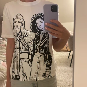 Vit t-shirt med coolt print - Vit t-shirt med ett stort print framtill som föreställer två personer i svart och silver. 