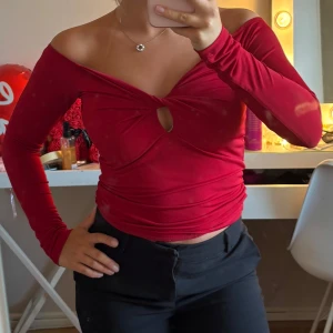 Röd offshoulder topp från Gina Tricot - Snygg röd offshoulder topp från Gina Tricot med lång ärm och twistad detalj framtill som skapar en liten cut-out. Toppens material är stretchigt och sitter tight. Perfekt för dig som vill sticka ut med en trendig look.