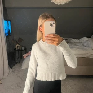 Vit croppad stickad tröja - Superfin vit croppad stickad tröja med rund halsringning och långa ärmar. Tröjan har ribbade muddar vid ärmslut och nederkant, vilket ger en snygg och enkel look. Perfekt att matcha med jeans eller kjol för en clean stil.