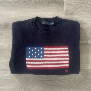 Ralph Lauren USA Logo🇺🇸 - Mörkblå stickad tröja från Polo Ralph Lauren med amerikansk flagga på bröstet och RL-broderi. Tröjan är i storlek L och passar mig fint som är runt 185cm. Inga defekter eller slitningar. Säljs väldigt dyrt nypris. Hör av dig vid funderingar🤩