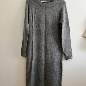 Grå stickad långklänning  - Mysig grå stickad långklänning från lager157 i storlek XS. Klänningen har rund halsringning, långa ärmar och en rak, avslappnad passform. Perfekt för kyliga dagar när du vill vara både bekväm och snygg.