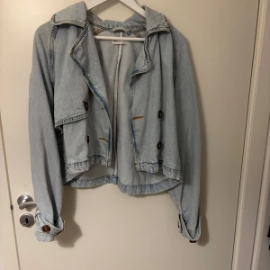 Ljusblå croppad jeansjacka med knappar - Säljer en ljusblå croppad jeansjacka med bruna knappar. 💙🩵köptes för 499kr