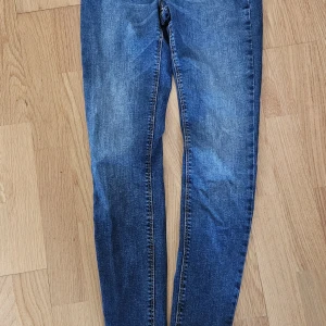 JDY Denim skinny jeans blå W27 L32 - Snygga blå skinny jeans från JDY Denim med klassisk femficksdesign och kontrastsömmar. Jeansen har en smal passform och är tillverkade i stretchigt denimtyg för en bekväm känsla. Perfekta för dig som gillar en tight look.