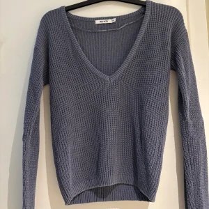 Grå stickad v-ringad tröja NA-KD - Säljer en grå stickad tröja från NA-KD i storlek XXS. Tröjan har en djup v-ringning, långärmade ärmar och en ribbad struktur som ger en snygg och avslappnad look. Perfekt att matcha med jeans eller kjol för en chill stil.