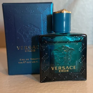 Versace Eros Eau de Toilette 5ml - Versace Eros Eau de Toilette i en snygg turkosblå glasflaska med guldiga detaljer och Medusa-huvudet på framsidan. Flaskan är fyrkantig och kommer med matchande blå kartong. Perfekt storlek för att ta med sig.