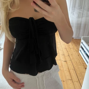 Svart bandeau tubtopp med volanger från shein - Supersnygg svart bandeau tubtopp med volangkant och smala band som kan knytas på olika sätt.  Ifrån SHEIN och strl xs 