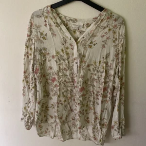 Blommig viskos blus stl 42 - Fin blommig viskos blus i str 42. Luftig passform med knappar hela vägen ner samt vid slutet av ärmarna. 