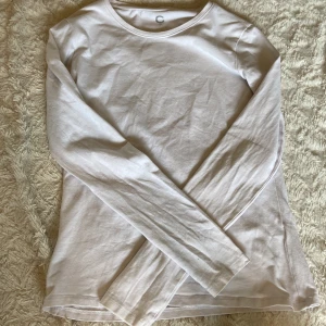 Vit långärmad tröja från Cubus  - En basic vit långärmad tröja från Cubus i storlek XS. Tröjan har rund halsringning och är gjord i mjuk bomull, perfekt att styla med jeans eller kjol. Enkel och clean look som funkar året runt.