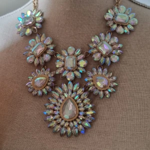 Glittrigt statement-halsband med stenar - Superfint statement-halsband med stora, glittriga stenar i regnbågsskimrande färger. Halsbandet har flera blommiga former med både droppformade och fyrkantiga stenar, infattade i guldfärgad metall. Perfekt för att sticka ut och ge extra bling till din outfit.