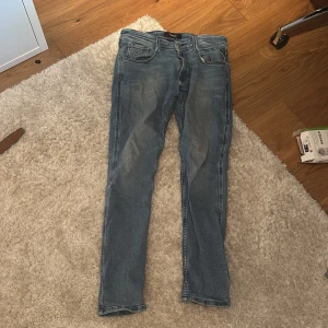 Replay Anbass ljusblå jeans, stl 32 32 - Säljer ett par snygga Replay Anbass jeans i ljusblå tvätt. Klassisk femficksmodell med smal passform och bekvämt stretchigt jeanstyg. Perfekta för dig som gillar en modern och stilren look. Storlek 32. Priset är pga det lilla hålet i byxan men inget som märks