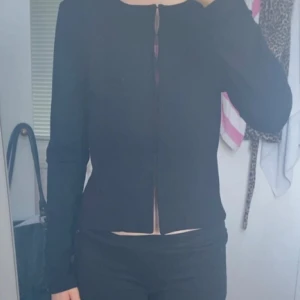 Svart figursydd cardigan jacka Å - Svart, stilren cardigan jacka från Å i figurnära modell. Jackan har lång ärm, dold knäppning framtill och är tillverkad i mjuk viskosmix med stretch för en bekväm passform. Perfekt för dig som gillar minimalistisk och clean stil.