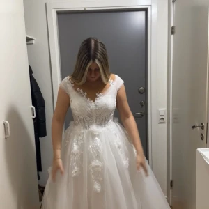 Bröllopskläning - princessklänning med fin blomspets å stort släp - Drömmig vit bröllopsklänning med v-ringad överdel, spetsdetaljer och blommiga broderier. Kjolen är i flera lager tyll som ger en riktig prinsessig känsla. Materialet är av bra kvalitet. Aldrig använd. Pris går att diskutera. Slöja finns att köpa till.
