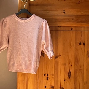 Ljusrosa stickad tröja Gina Tricot - Supersöt ljusrosa stickad tröja från Gina Tricot med puffiga trekvartsärmar och ribbade muddar. Perfekt för dig som gillar en feminin och chill stil. Mjuk och skön, passar till både jeans och kjol.