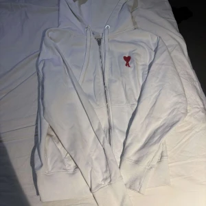 Vit hoodie med rött hjärta från Ami - Snygg tröja från ami säljs för bra pris hör av er vid fundering!!!