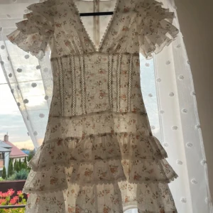 blommig kortklänning med volanger - Supersöt kortklänning i ljusbeige med små blommor och hjärtmönster. Väldigt lik i passform som den trendiga zara klänningen