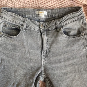 Ljusgrå bootcut jeans från Gina Tricot - Snygga ljusgrå jeans från Gina Tricot i bootcut-modell. Jeansen har klassisk femficksdesign, bälteshällor och knappgylf. Materialet är mjukt och stretchigt jeans, perfekt för en avslappnad men trendig look. Storleken är 158.