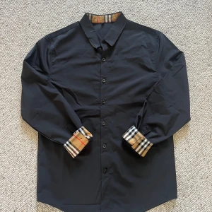 Burberry skjorta  - En svart burberry skjorta i storlek S men det stor xl men det är S och den är i nytt skick. Pris kan diskuteras och skriv om du har några frågor. 