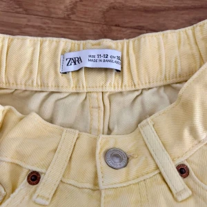 Gula jeansshorts från Zara - Snygga ljusgula jeansshorts från Zara med hög midja och fransig kant nedtill. Klassisk femficksmodell med knapp och dragkedja framtill. Perfekta för varma sommardagar och ger en fräsch vibe till din outfit.