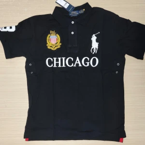 Svart Polo Ralph Lauren Chicago t-shirt - Svart t-shirt från Polo Ralph Lauren med broderad logga, stor CHICAGO-text och guldfärgad patch framtill. Klassisk pikékrage, vita detaljer och stor siffra 3 på ryggen och ärmen. Snygg och sportig stil, perfekt för dig som gillar streetwear. Vid fundering skicka dm :)