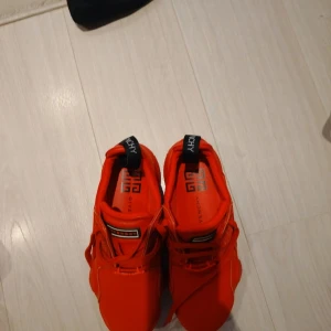 Röda sneakers från Givenchy strl 40 - Snygga röda Givenchy sneakers med chunky sula och coola detaljer. Skorna har snörning, meshpartier på sidorna och inslag av mocka och skinn. Givenchy-logga på plösen och hälflik. Perfekta för dig som vill sticka ut med lyxig streetstyle.