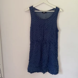 Blå prickig sommarklänning Bik Bok - Supersöt blå kortklänning från Bik Bok med vita prickar. Ärmlös modell med rund halsringning och avslappnad passform. Perfekt för varma dagar och enkel att styla med sneakers eller sandaler. Tunt och luftigt material som känns skönt mot huden.