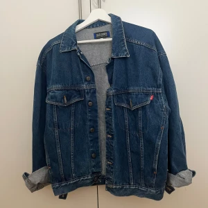Oversized jeansjacka från Jack & Jones - Säljer en klassisk blå jeansjacka från Jack & Jones med snygga bronsfärgade knappar och två bröstfickor med lock. Jackan har en oversized passform och långa ärmar som kan vikas upp. Köpt för längesen och använd ett fåtal gånger 