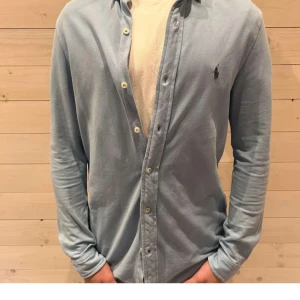 Ljusblå skjorta från Ralph Lauren - Snygg ljusblå skjorta från Ralph Lauren med klassisk krage och knappar framtill. Skjortan har lång ärm och ikoniska broderade loggan på bröstet. Perfekt för dig som gillar stilrena och tidlösa plagg.kan gå ner i pris vid snabb affär är i storlek 18 som motsvarar xs-s