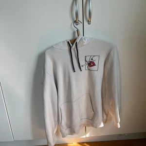 Vit hoodie med konstnärligt tryck - Vit hoodie från carlings  med svart snörning och stor ficka framtill.väldigt använd och går väll att piffa upp för den händige . Storlek L/XL