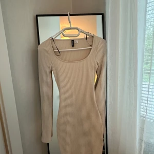 Beige ribbad långärmad klänning H&M - Snygg beige ribbad klänning från H&M med lång ärm och tight passform. Klänningen är kort och har en rundad urringning, perfekt för dig som gillar en enkel men stilren look.