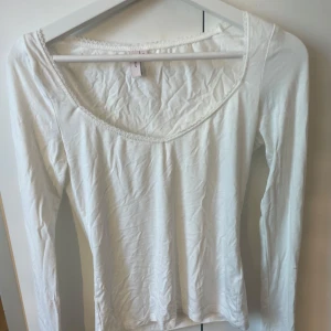 Vit långärmad topp med spetskant Nelly - Supersöt vit långärmad topp från Nelly i mjuk bomull. Djup rundad ringning med fin spetskant som ger en feminin touch. Perfekt att styla med jeans eller kjol för en enkel men snygg look. Aldrig använd då jag köpte fel strorlek.