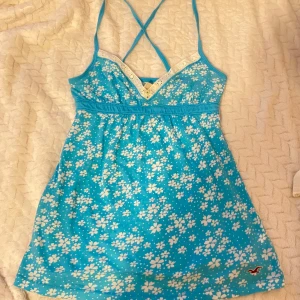  Hollister babydoll🩵 - Supersöt topp från Hollister med vita blommor, smala korsade axelband och v-ringad spetskant upptill. 