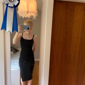 Svart tight klänning från Amisu - Svart figurnära klänning från Amisu med smala axelband och enkel, stilren design. Klänningen är midilång och har en tight passform som framhäver siluetten. Perfekt för dig som gillar minimalistisk och klassisk stil.