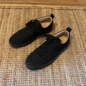 Louboutin skor - Säljer ett par svarta sneakers från Christian Louboutin i mocka med svarta nitar på tån. Kommer med originalkartong och äkthetsbevis. Vid fler bilder är det bara att höra av sig!