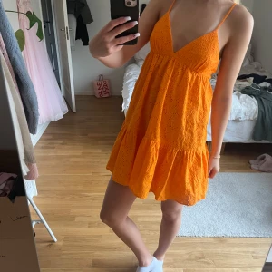 Orange broderad sommarklänning Zara - Superfin orange kort klänning från Zara med broderade blommor och tunna axelband. Klänningen har v-ringning, volangkant nertill och öppen rygg med knyt. Perfekt för varma dagar och ger en färgklick till garderoben. Aldrig fårt använding för den så väldigt bra skick o passar bra utomlands💕Skulle säga att den sitter som en Xs/s🥰