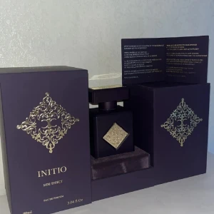 Initio Side Effect Eau de Parfum 90ml - Lyxig parfym från Initio, Side Effect, i en elegant svart fyrkantig flaska med guldfärgade detaljer och dekorativt mönster. Flaskan rymmer 90ml och har en exklusiv känsla med sin matta finish och tunga design. Kommer i en snygg ask med matchande guldmönster.