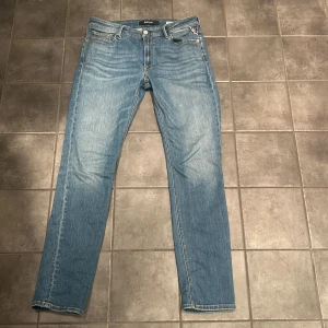 Ljusblåa Reaplay jeans  - Säljer ett par ljusblå jeans från Replay i klassisk straight fit. Jeansen har fem fickor, snygga slitningar och kontrastsömmar. Tillverkade i bomull och perfekta för en avslappnad stil. Ikonisk bakficka med Replay-logga. 1600kr