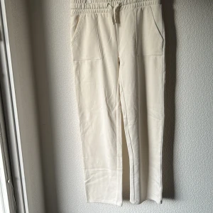 Vita mjukisbyxor med snörning - Snygga vita mjukisbyxor med resår och snörning i midjan. Byxorna har raka ben, stora fickor fram och bak samt en avslappnad passform. Oanvända 