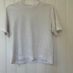 Vit basic t-shirt från Gina Tricot - En klassisk vit t-shirt från Gina Tricot, basically basics-kollektionen. T-shirten har rund hals, korta ärmar och är gjord i mjuk bomull. Perfekt till jeans eller shorts för en clean och enkel look.