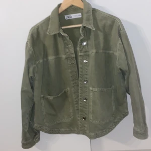 Grön overshirt från Zara i bomull - Snygg grön overshirt från Zara i bomull med klassisk krage, stora fickor framtill och silvriga knappar. Perfekt lager-på-lager-plagg med avslappnad passform och stilren look. Passar till både jeans och kjol.