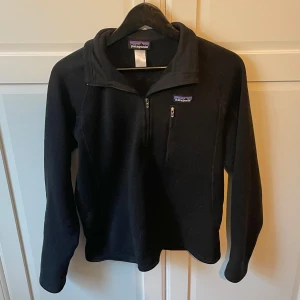 Patagonia half zip fleece - Svart fleece-tröja från Patagonia med halv dragkedja och liten bröstficka med zip. Mjuk och varm med hög krage, perfekt för kyliga dagar. Storlek S. Skriv vid frågor!