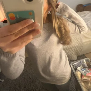 Ljusgrå stickad tröja med rund hals - ljusgrå stickad tröja med rund hals och långa ärmar. Tröjan har ribbade muddar vid ärmslut och nederkant, vilket ger en clean och enkel look. Perfekt för lager-på-lager och chill dagar.