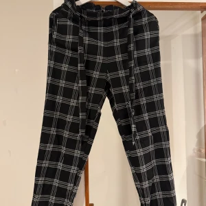 Svarta rutiga byxor  H&M - Svarta byxor med vitt rutmönster från H&M i storlek 38. Lätta och sköna, Jag är 157cm och benen är i perfekt längd. 