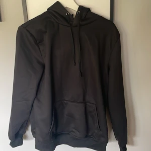 Svart hoodie med teddyfoder - Mysig svart hoodie med fluffigt beige teddyfoder på insidan. Tröjan har ficka framtill, snörning i huvan och långa ärmar. Perfekt för kalla dagar när du vill vara både bekväm och stilren.