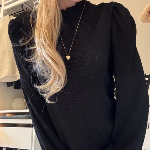 Svart  blus med puffärm - Säljer en svart plisserad blus med högt rynkat hals och långa puffärmar. Storlek Xs/s