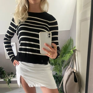Randig svartvit tröja från Vero Moda - Säljer en svart stickad tröja från Vero Moda med vita horisontella ränder. Tröjan har rund halsringning och långa ärmar. Perfekt att styla med kjol eller jeans för en chill och snygg look.