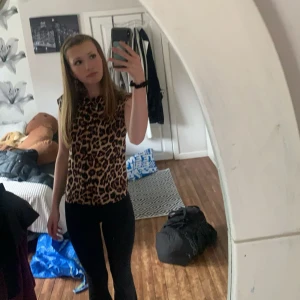 Leopardmönstrad topp - Säljer en snygg ärmlös topp i strl XS från lager 157 med leopardmönster i brunt, beige och svart. Toppen har rak passform och rund halsringning, perfekt för dig som vill sticka ut lite extra. Mjuk och stretchig känsla, superenkel att styla med jeans eller kjol.