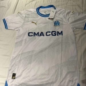 Marseille hemmatröja Puma vit/blå - För dig som vill ha den franska stilen, marsielle t shirt väldigt snygg som passar till väldigt mycket, helt ny aldrig använd, för mer frågor eller intresse finns jag i DM