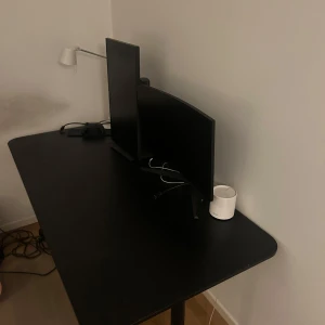 Svart trä skrivbord - Säljer ett svart trä skrivbord med rektangulär form. Bordet har en slät yta och robusta ben i metall. Perfekt för hemmakontoret eller gaminghörnan. 