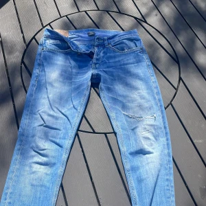 Dondup George 33 - Säljer ett par dondup jeans i modellen George. De har slitningar på benen och är ljus blåa. 